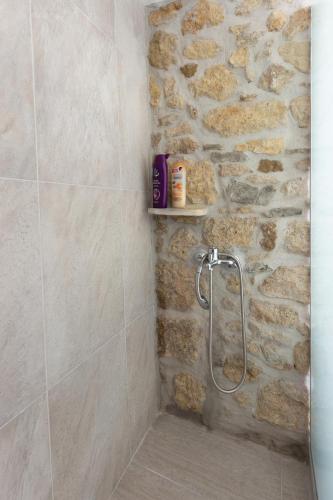 a shower in a bathroom with a stone wall at Iliopetra House in Sívas