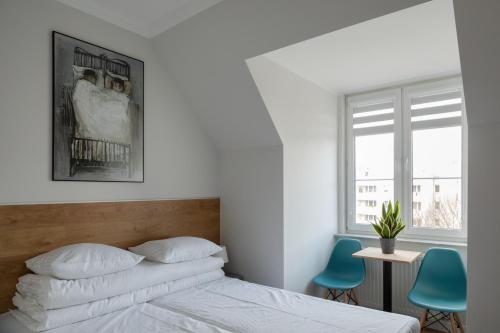 a white bedroom with a bed and two blue chairs at MoHo XL in Wrocław