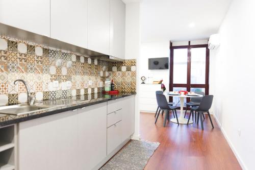 ポルトにあるAPOSENTUS - Your Home in Martires da Liberdadeのキッチン(白いキャビネット、テーブル、椅子付)