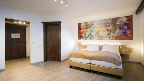 a bedroom with a bed and a painting on the wall at Family Hotel Schloss Rosenegg in Fieberbrunn