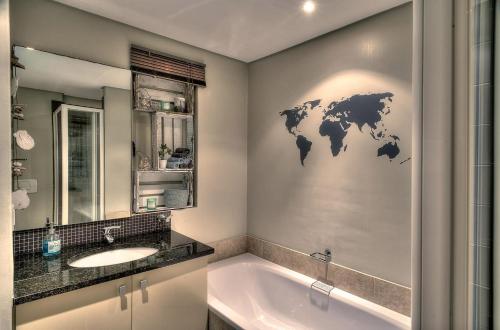 un baño con lavabo y un mapa mundial en la pared en Portico 802 en Bloubergstrand