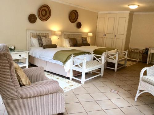 1 Schlafzimmer mit 2 Betten, einem Sofa und Stühlen in der Unterkunft Malvern Manor Country Guest House in George