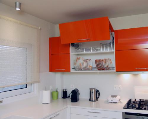 a kitchen with orange cabinets and white counters at The Villa of the Winds in Néa Kíos