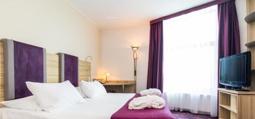 a hotel room with a bed with a teddy bear laying on it at Galaxy Hotel in Kraków