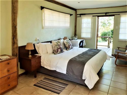 - une chambre dotée d'un grand lit avec des draps et des oreillers blancs dans l'établissement Elandsview Guesthouse, à Rorkeʼs Drift