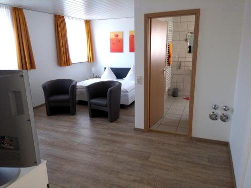 a hotel room with a bed and chairs and a bathroom at Ferienwohnungen Lippold in Bad Salzuflen