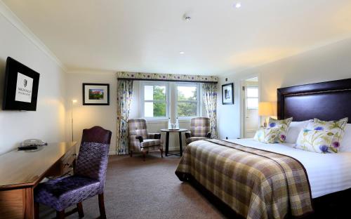 a bedroom with a bed and a desk and a window at Macdonald Morlich Hotel at Macdonald Aviemore Resort in Aviemore