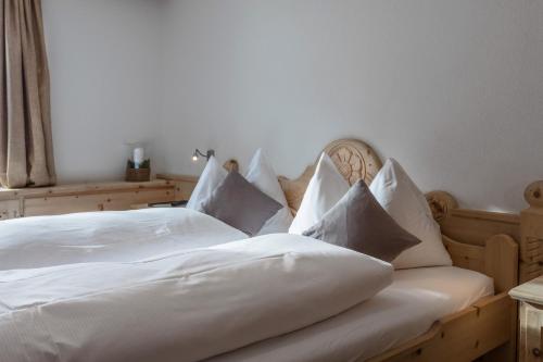 a bedroom with a white bed with white sheets and pillows at Hotel Klarer in Zuoz