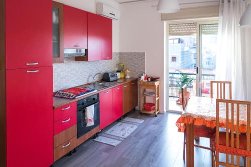 シラクーサにあるCasa Gentileのキッチン(赤いキャビネット、テーブル付)