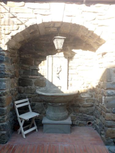 a stone wall with a chair and a fountain in a stone building at Rocca Palazzaccio in Impruneta