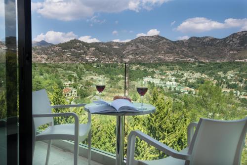 a table with two glasses of wine and a book at Rodon Hotel and Resort in Agros