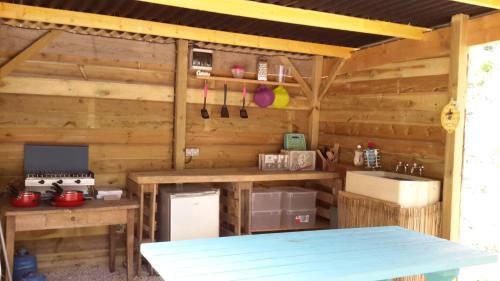 - une cuisine dans une cabane en bois avec une table dans l'établissement Camping Bois de St Hilaire, à Chalandray