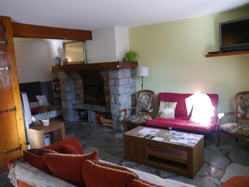 sala de estar con sofá rojo y chimenea en Le Hameau de Campan, en Sainte-Marie-de-Campan