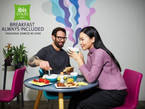 a man and a woman sitting at a table with a plate of food at ibis Styles Warszawa City in Warsaw