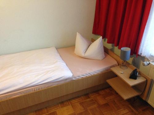 a small bed with two pillows on top of it at Hotel Deutsches Haus in Kurort Gohrisch