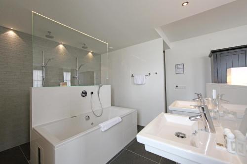 a bathroom with a sink, mirror, and bathtub at Grand Hotel Alkmaar in Alkmaar