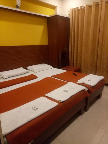 a bedroom with two beds with white towels on them at hotel sangeeth lodging in Mysore