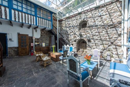 a patio with chairs and a stone wall at X.O Art House in Cusco