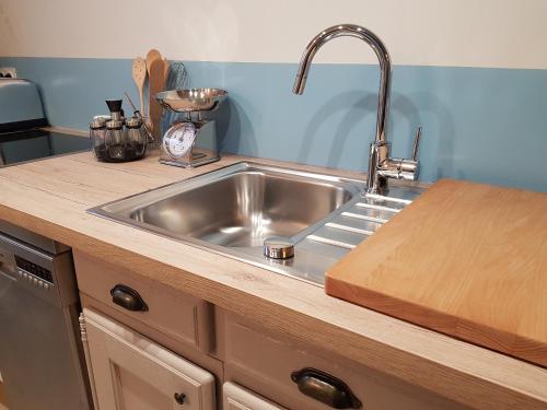 a stainless steel sink in a kitchen with a wooden counter at Les Bruyeres in Sotteville-lès-Rouen