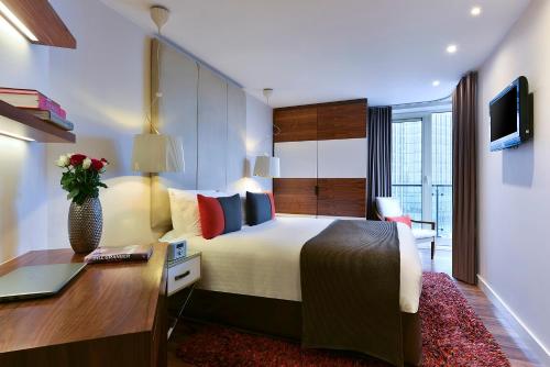 a bedroom with a bed and a desk with a laptop at Fraser Place Canary Wharf in London