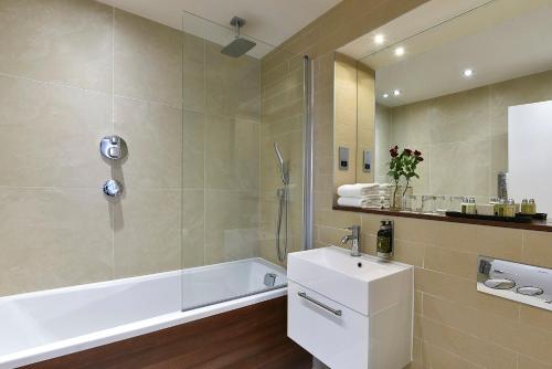 a bathroom with a tub and a sink and a shower at Fraser Place Canary Wharf in London