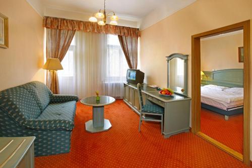 a hotel room with a bed and a desk and a chair at Ensana Svoboda in Mariánské Lázně