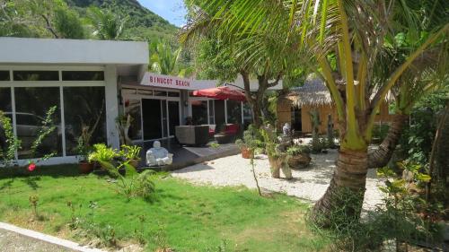 a building with a palm tree in front of it at Binucot Beach Resort in Ferrol