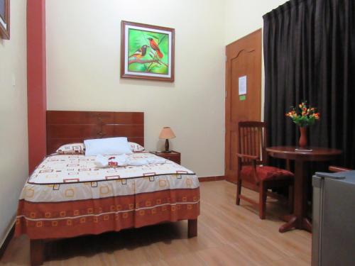 a bedroom with a bed and a table and a chair at Alojamiento El Cardenal in Iquitos