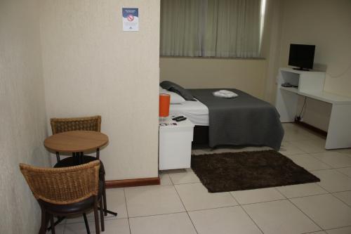 a small room with a bed and a table and chairs at Blu Apart Hotel in Mogi-Guaçu