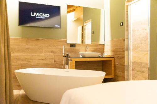 a bathroom with a large white tub and a sink at Hotel Centro's in Livigno