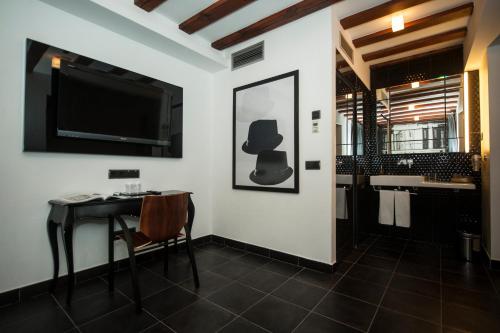 a bathroom with a table and a television and a sink at Posada del León de Oro Boutique Hotel in Madrid