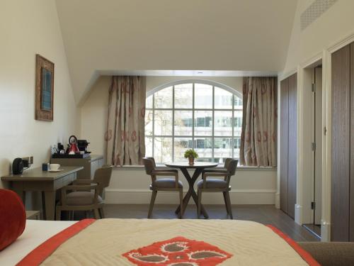 a bedroom with a table and chairs and a window at The LaLit London in London