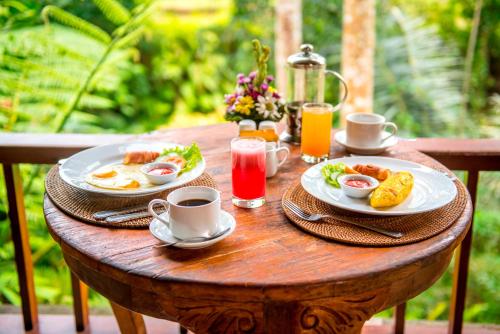 een houten tafel met borden ontbijtproducten erop bij Alam Dania Cottage in Ubud