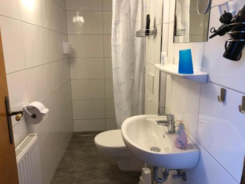 La salle de bains blanche est pourvue de toilettes et d'un lavabo. dans l'établissement Messezimmer 4u, à Düsseldorf