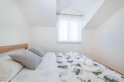 a white bedroom with a bed with a window at Apartments Matej in Pag