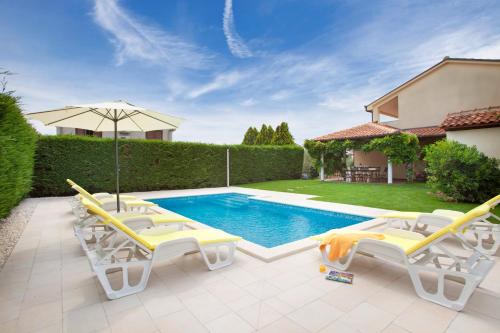 a backyard with a pool with chairs and an umbrella at Villa Aurata in Ližnjan (Haus für 8-9 Personen) in Ližnjan