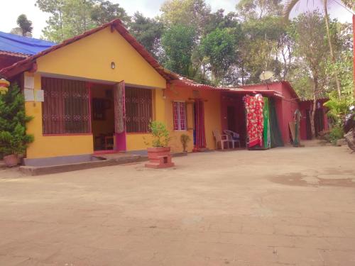 a yellow and red house with a courtyard at Dreams Home Estate Stay in Suntikoppa