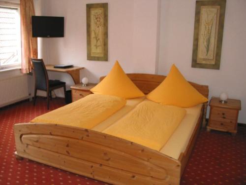 a bedroom with a wooden bed with yellow pillows at Hotel Gästehaus Theresia Garni in Mühlheim an der Donau