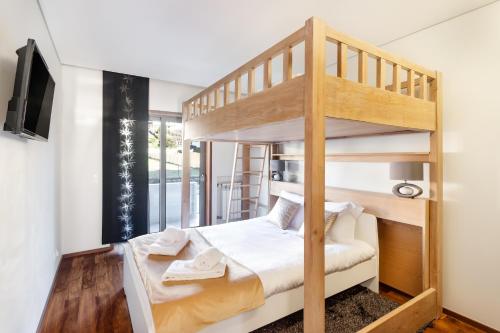 a bedroom with a bunk bed with a ladder at Pink Apartment - Spacious Apartment with Pool in Viana do Castelo