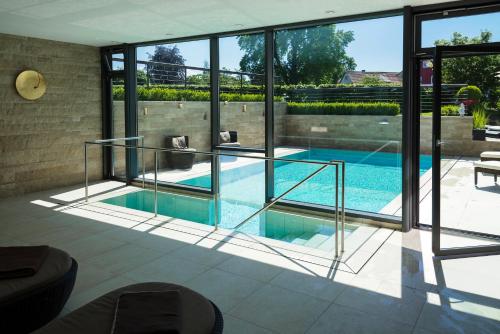 a house with a swimming pool with glass walls at Hotel Restaurant Spa Torkel in Nonnenhorn