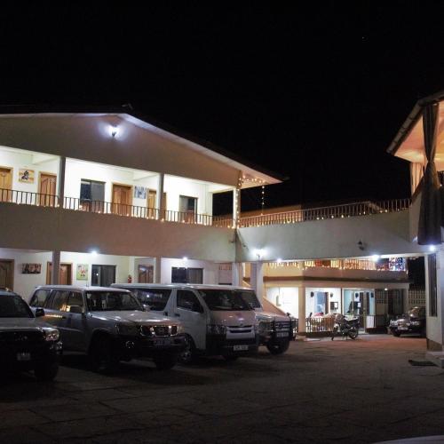 two cars parked in front of a building at night at Paloma Guest House in Kenema