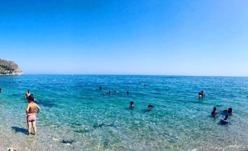 a group of people in the water at a beach at Seafront House Gabbiano Azzurro in Santa Flavia