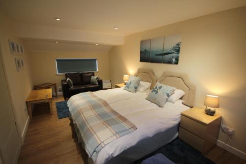 a bedroom with a large white bed and a chair at Easter Arr Courtyard Apartment in Nairn