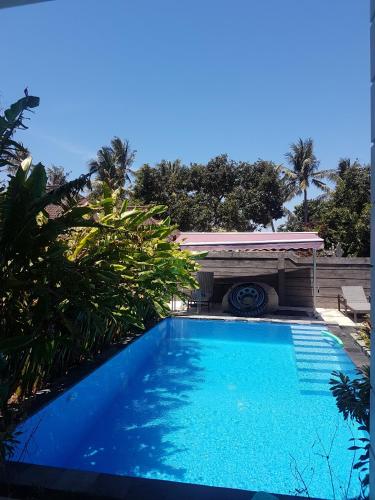 a large blue swimming pool with a gazebo at Vila Troja Kubu in Tulamben
