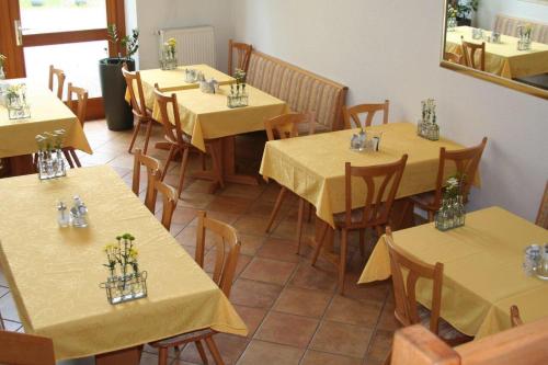 restauracja ze stołami i krzesłami z żółtą tkaniną w obiekcie Hotel Gästehaus Theresia Garni w mieście Mühlheim an der Donau