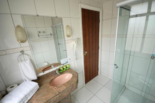 y baño con lavabo rosa y ducha. en Caravelle Palace Hotel, en Curitiba