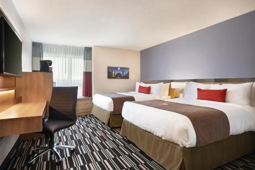 a hotel room with two beds and a desk at Microtel Inn & Suites by Wyndham Val-d Or in Val-dʼOr