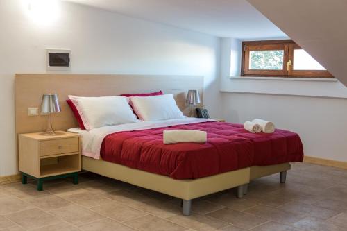 Il Moscardino Country Resort في سيرا سان برونو: غرفة نوم بسرير كبير مع بطانية حمراء
