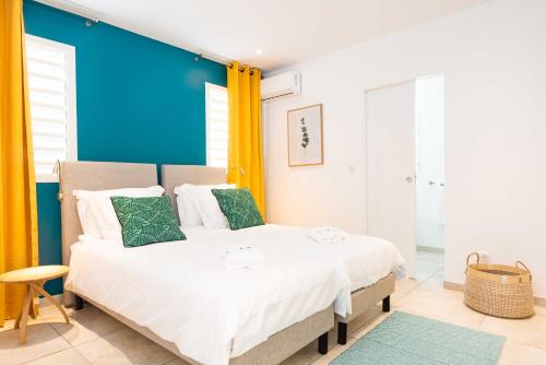 a bedroom with a large white bed with green pillows at Villas Rock & Beach in Le Diamant