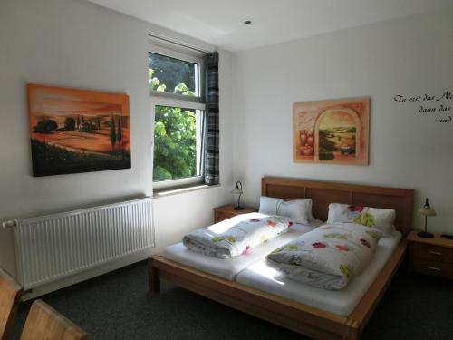 ein Schlafzimmer mit einem Bett mit zwei Kissen und einem Fenster in der Unterkunft Raffelberger Hof in Mülheim an der Ruhr